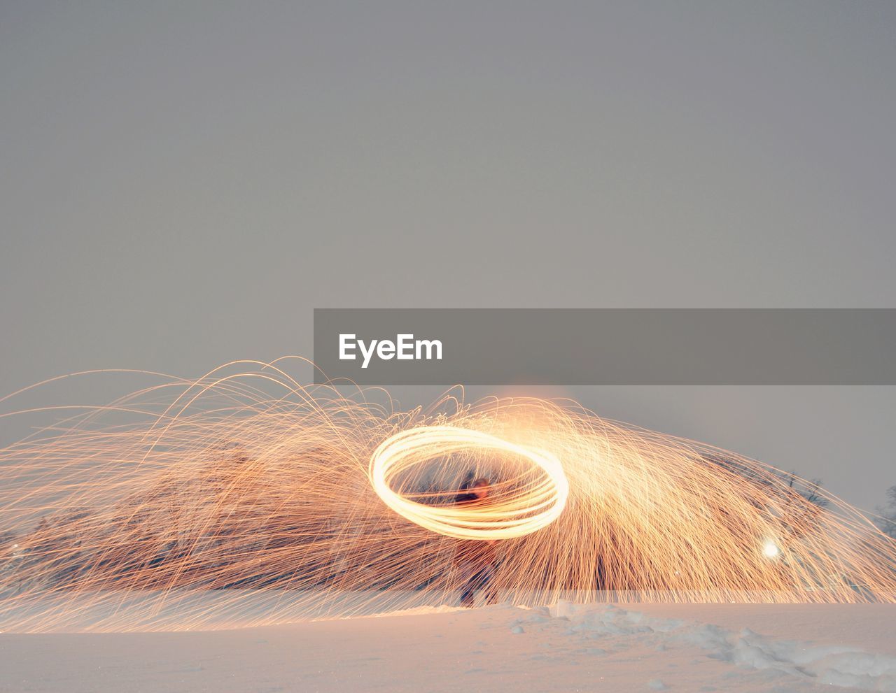 Light trails on snow against clear sky at night