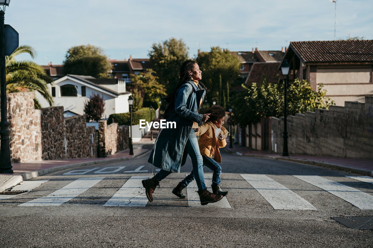 Woman and girl running while crossing road at city