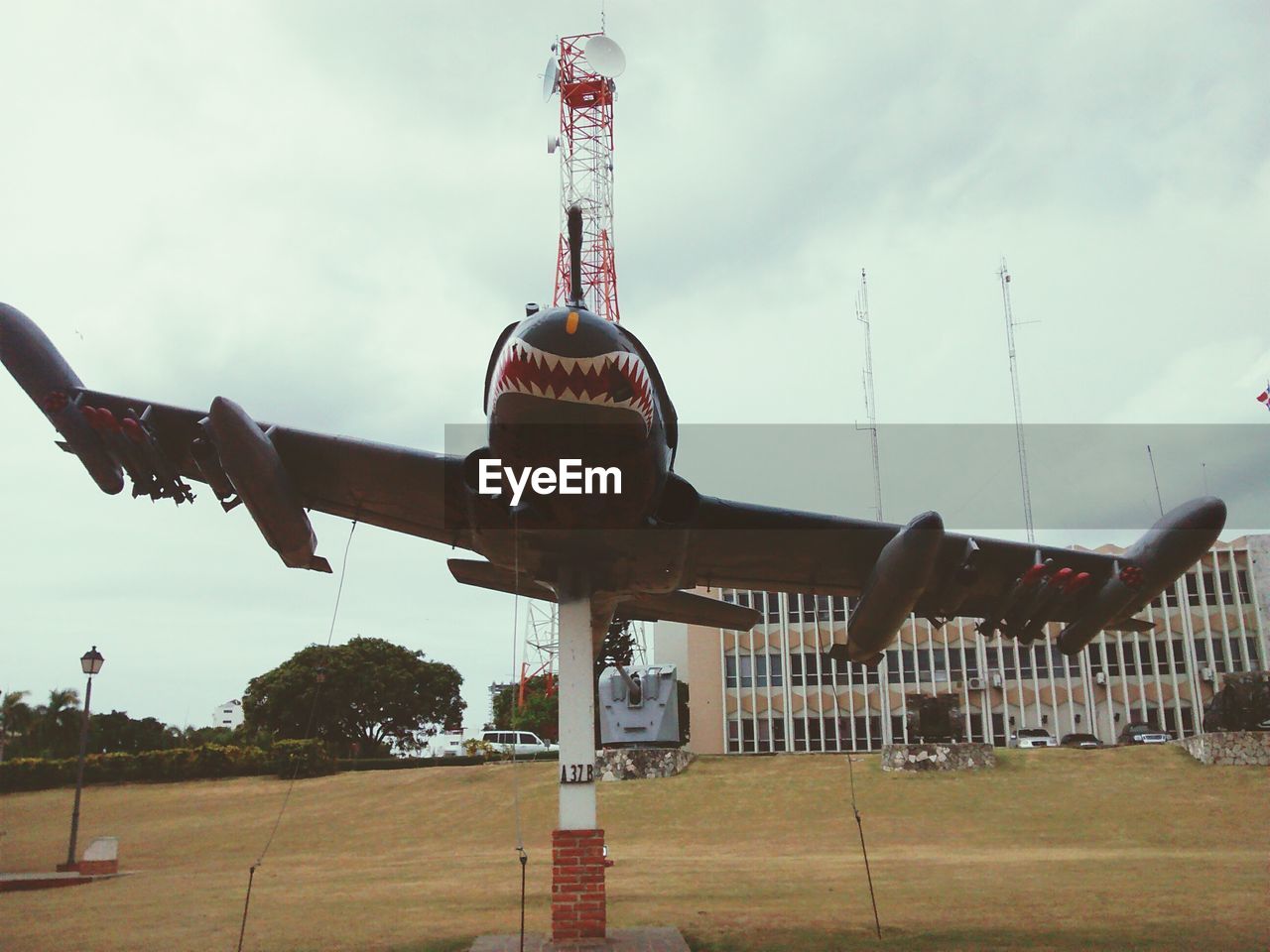 Airplane model on field against building and sky