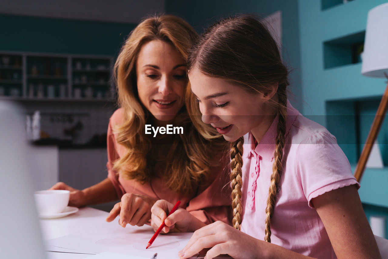 Cheerful mother and daughter discussing over studies