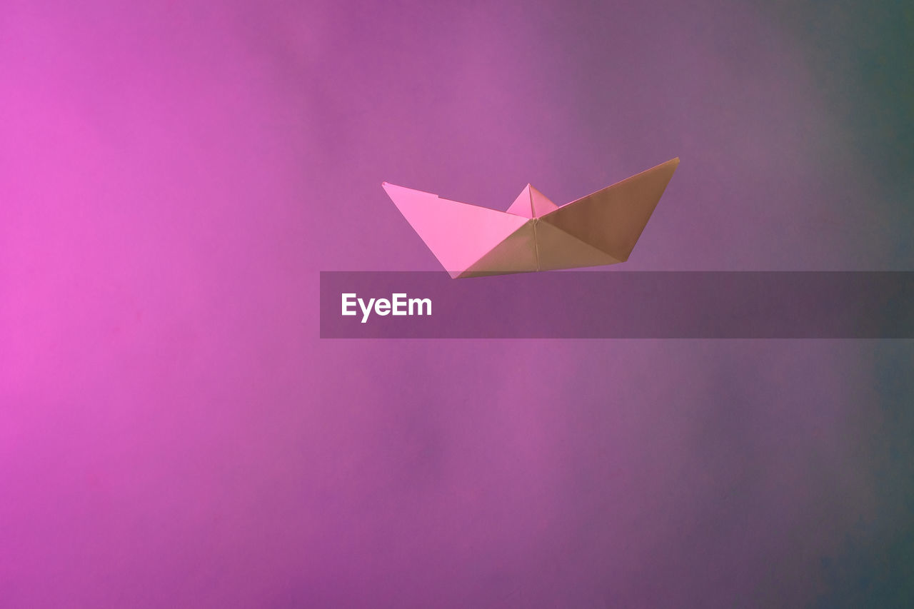 Close-up of paper boat with smoke against pink background