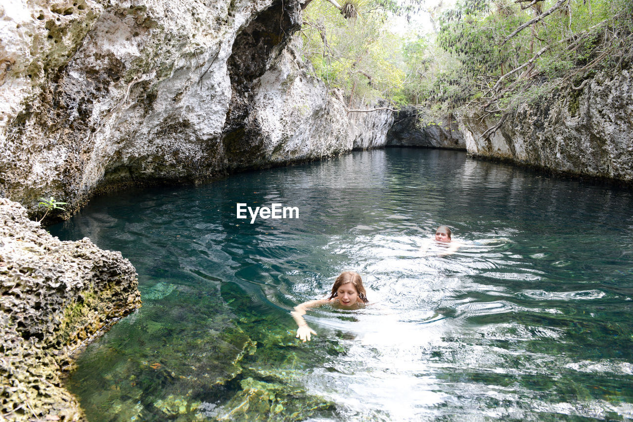 HIGH ANGLE VIEW OF DOG SWIMMING ON RIVER AMIDST ROCKS