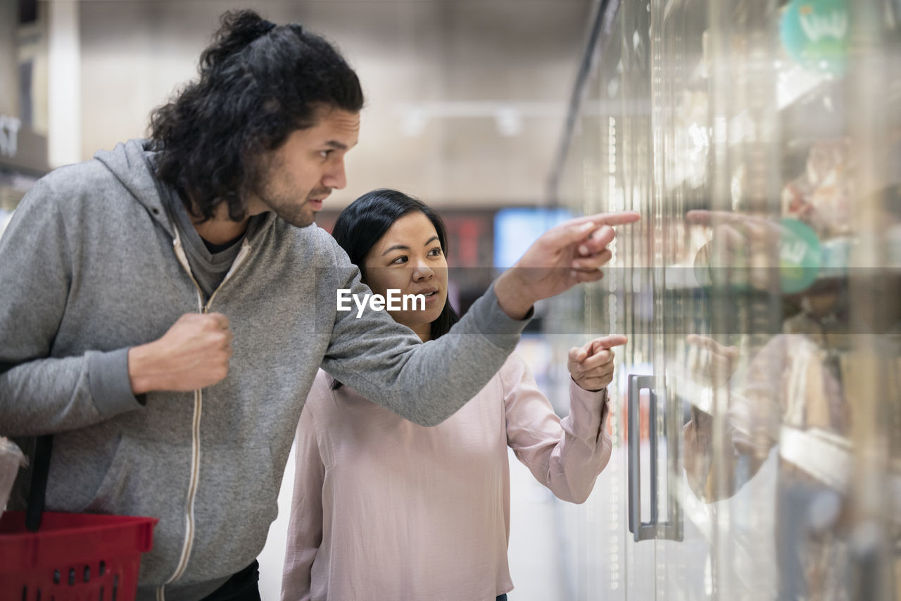 Young couple shopping during inflation in supermarket