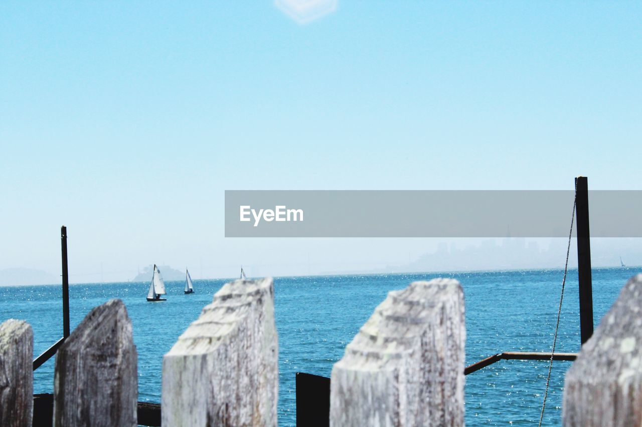 WOODEN POSTS IN SEA AGAINST SKY