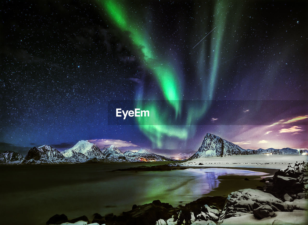 Scenic view of sea and mountains against sky at night