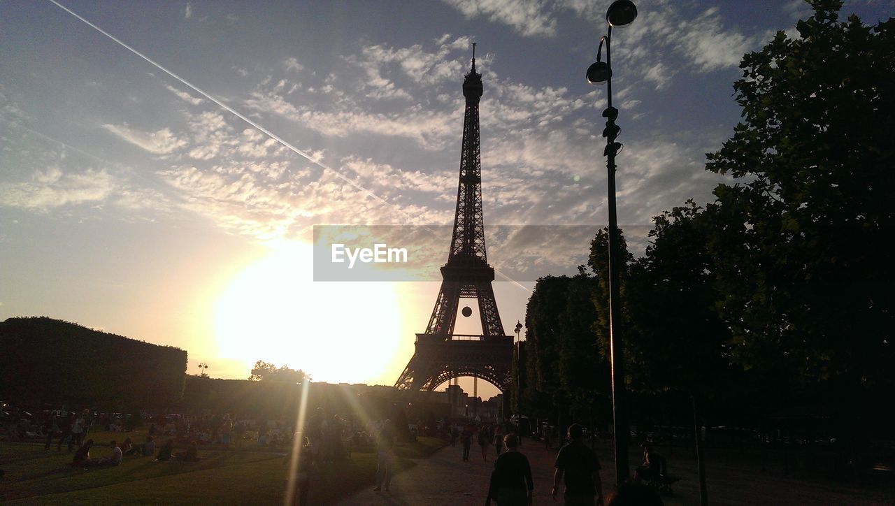 People by eiffel tower against sky during sunset in city