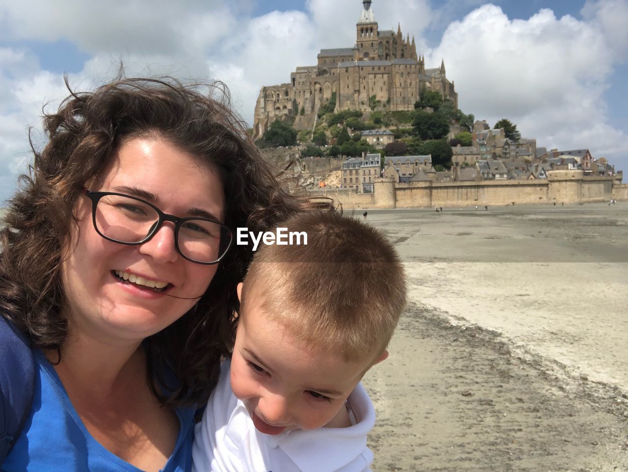 Portrait of smiling woman carrying son against castle