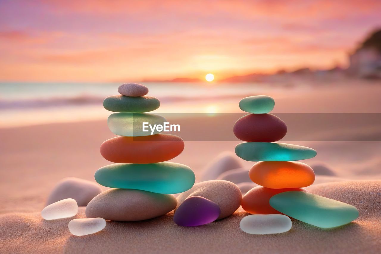 sunset, land, sky, multi colored, nature, no people, beach, blue, sand, water, sea, focus on foreground, cloud, tranquility, large group of objects, orange color, environment, zen-like, tranquil scene, outdoors, close-up, sunlight