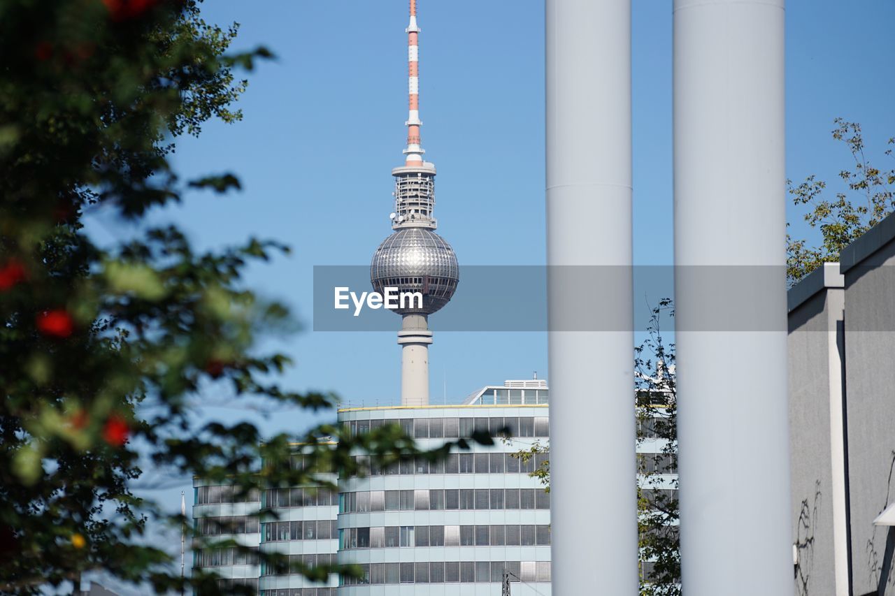 Berlin tv tower in city against blue sky