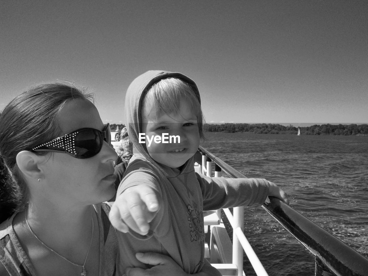 Portrait of child with mother in boat at sea against sky on sunny day