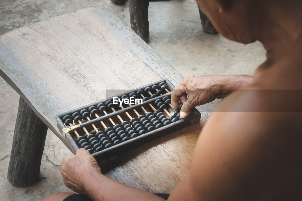 High angle view of shirtless man counting using abacus