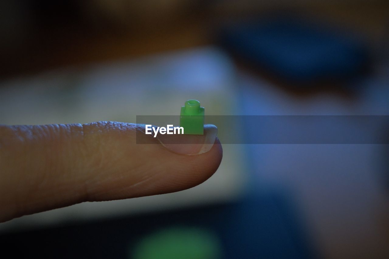 Cropped hand of woman holding toy block on finger