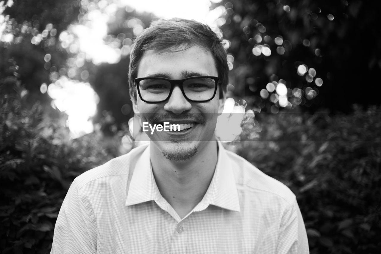 Portrait of smiling young man wearing eyeglasses outdoors