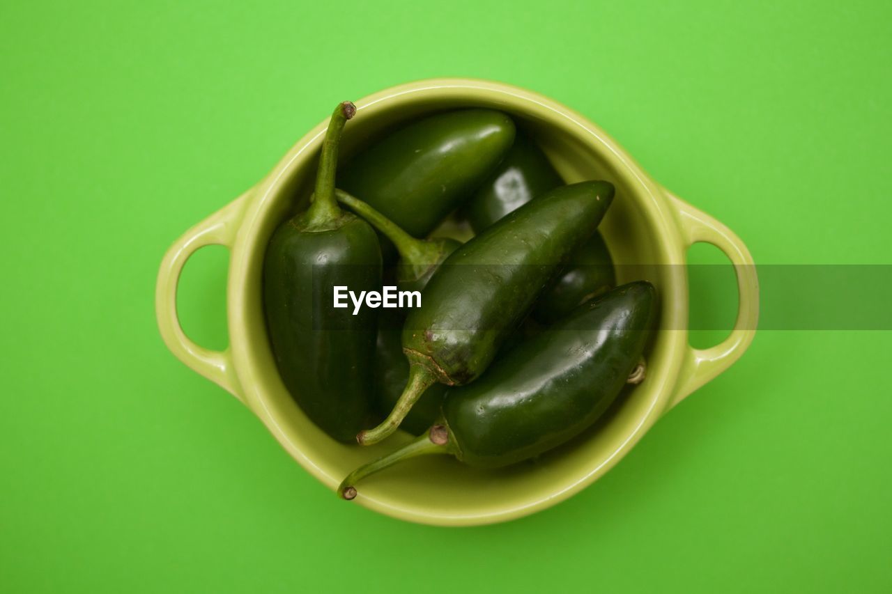 High angle view of chili peppers over green background