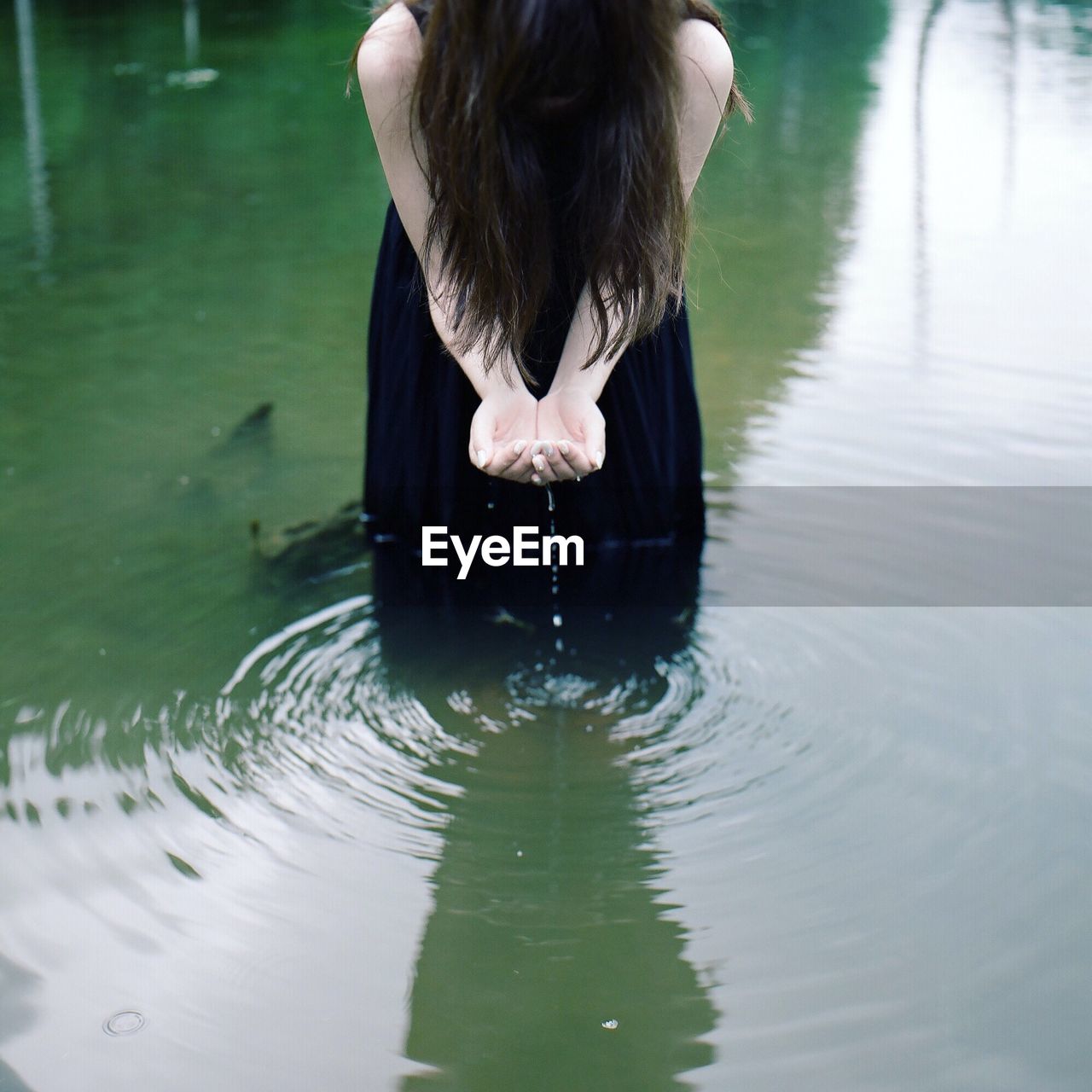 Midsection of woman collecting water in lake