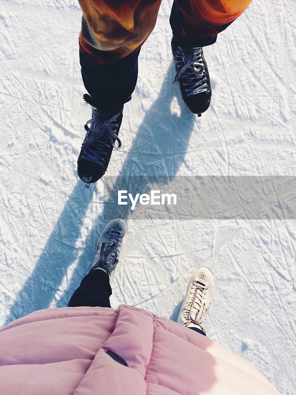 Low section of people ice-skating on snow during winter