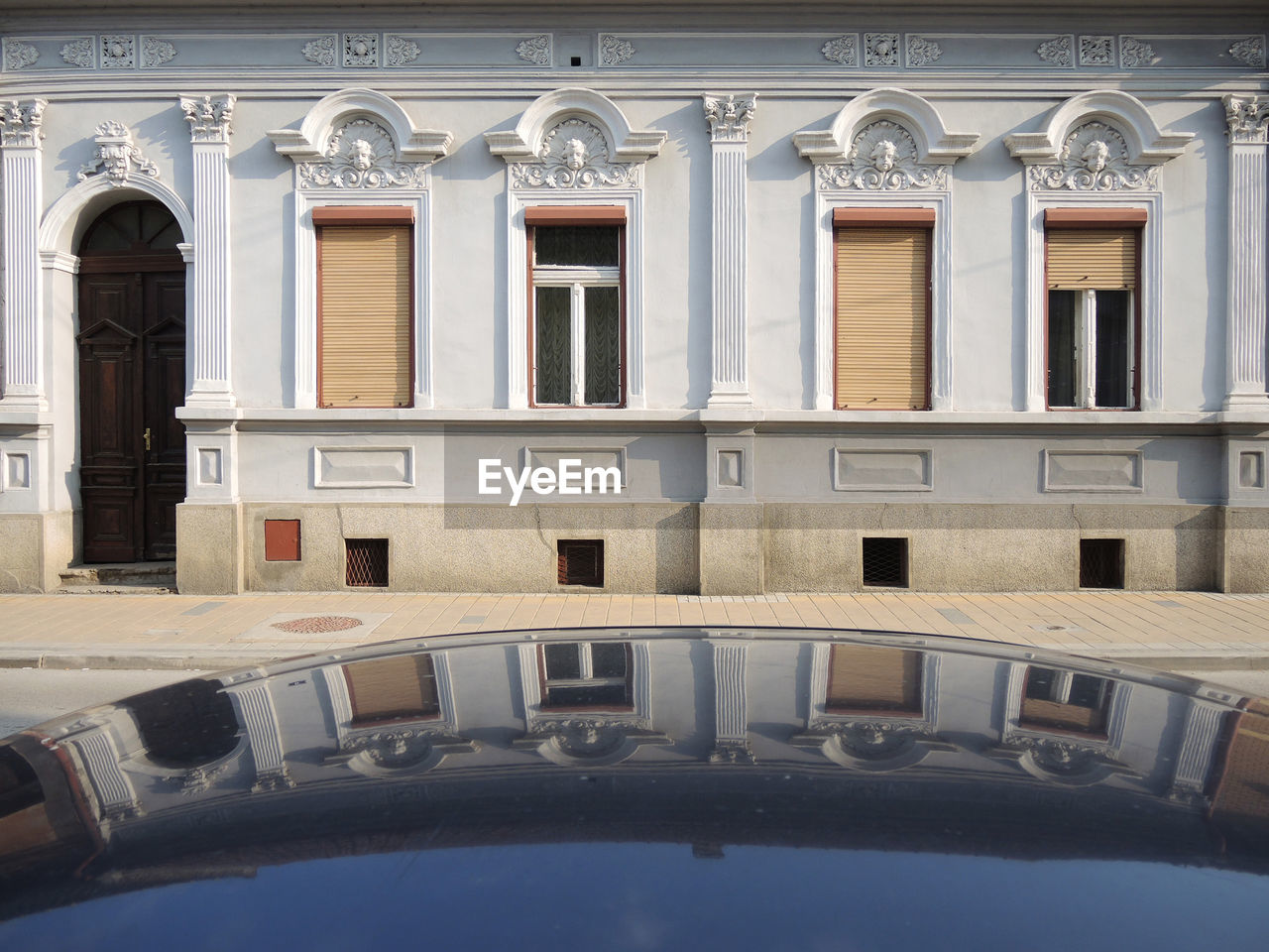 Front of house with reflection of windows on the top of the car