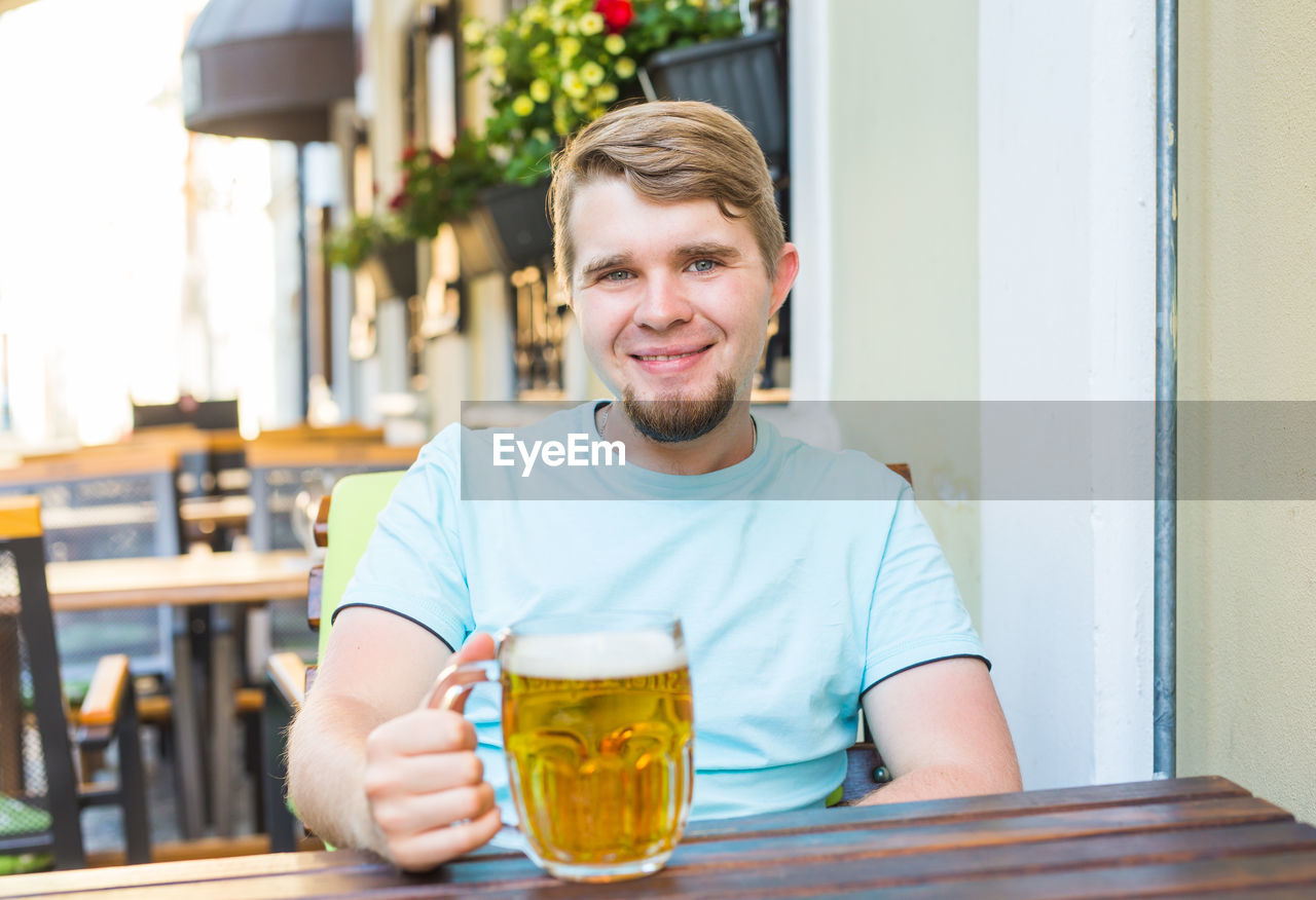 Portrait of smiling man holding beer glass at bar