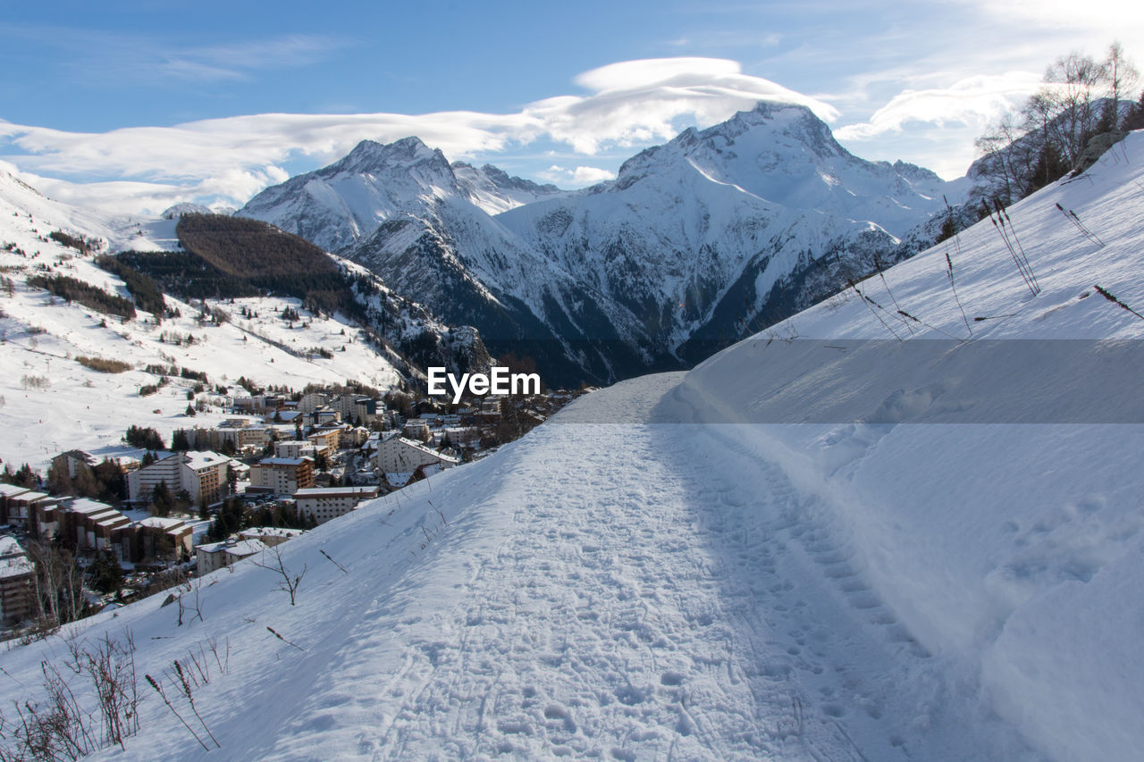 snow, winter, cold temperature, mountain, scenics - nature, mountain range, environment, landscape, beauty in nature, piste, nature, sky, snowcapped mountain, cloud, travel destinations, travel, white, no people, ski mountaineering, tranquil scene, architecture, resort, winter sports, land, tranquility, mountain peak, day, ski touring, outdoors, ridge, frozen, ice, tourism, non-urban scene, built structure, building, building exterior, sunlight, blue, idyllic