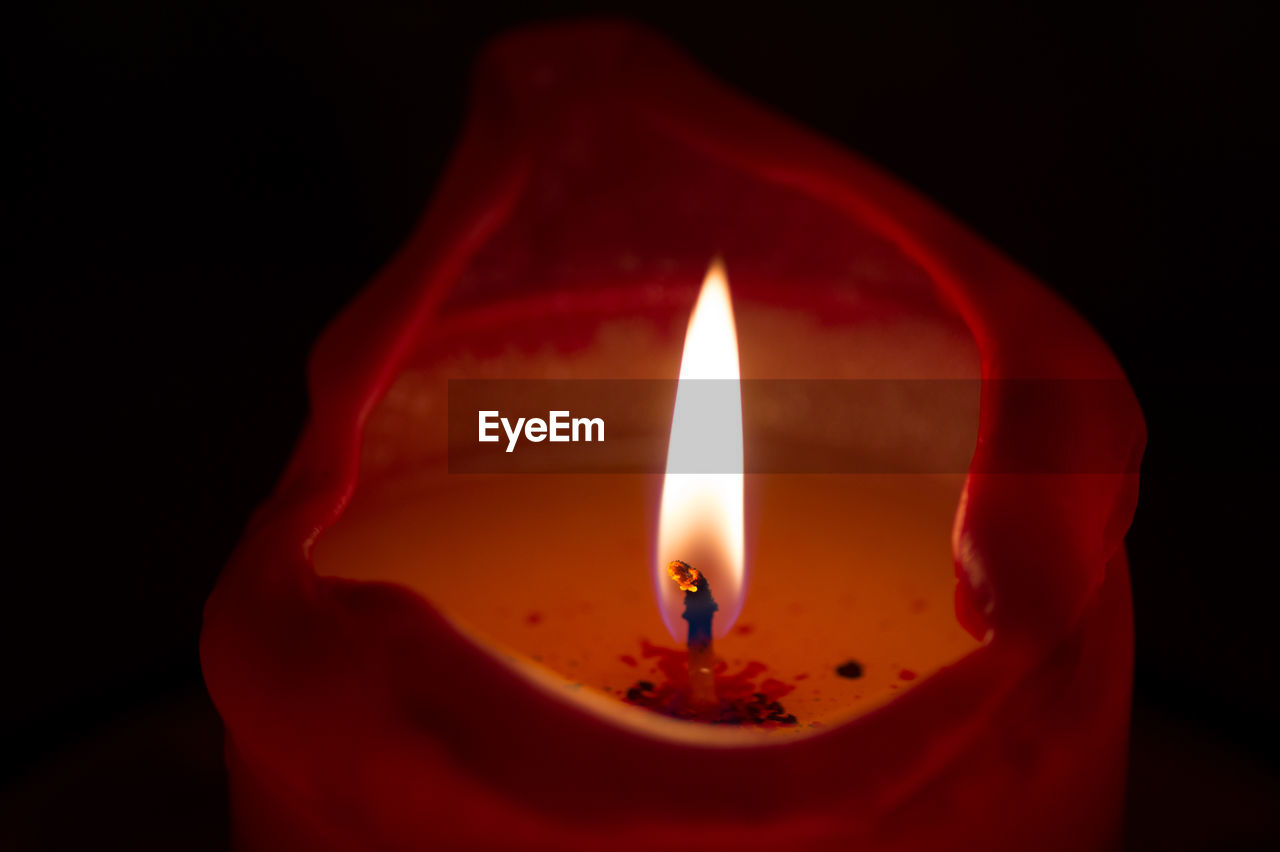 Close-up of illuminated candle against black background