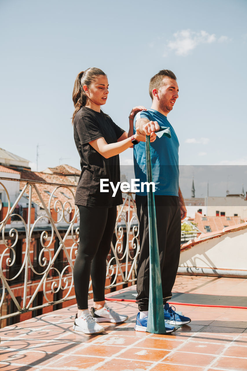 A couple doing training with rubber resistance band on their fooftop