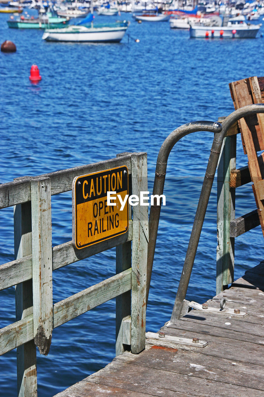 Warning sign on railing of boat in sea