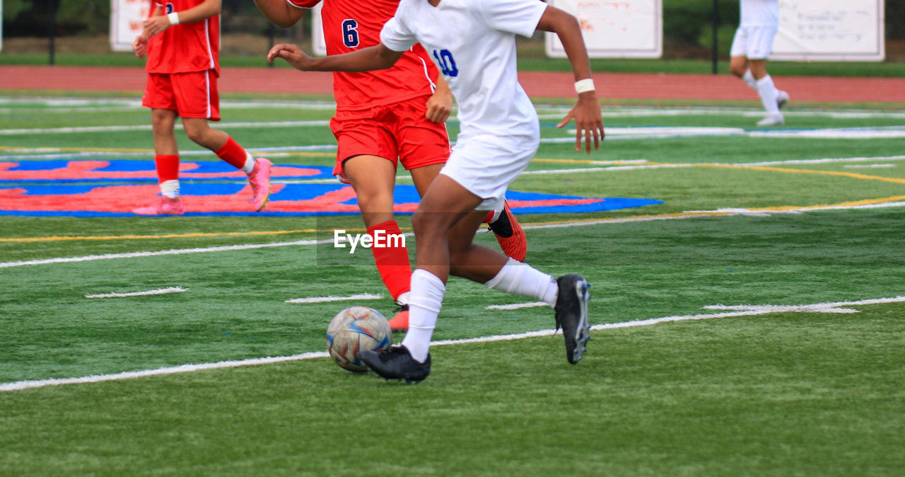 High school boys playing soccer dribbling the ball by the defender during a game.