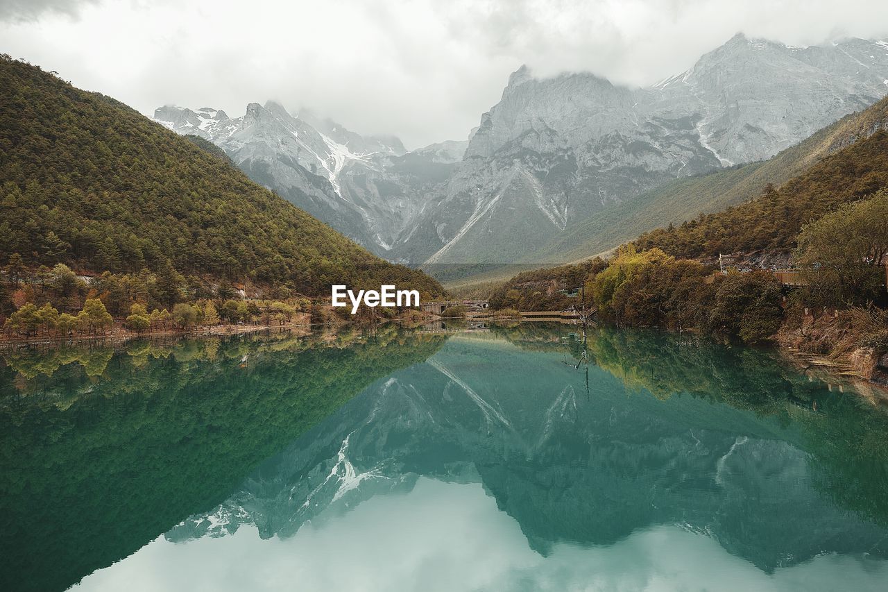 Scenic view of lake by mountains against sky