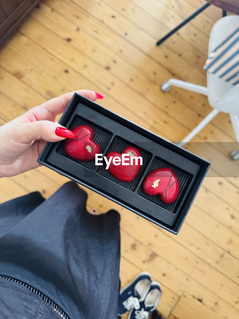 hand, red, one person, indoors, adult, holding, high angle view, wood, lifestyles, technology, hardwood floor, leisure activity, table, men, women, home interior, finger, flooring