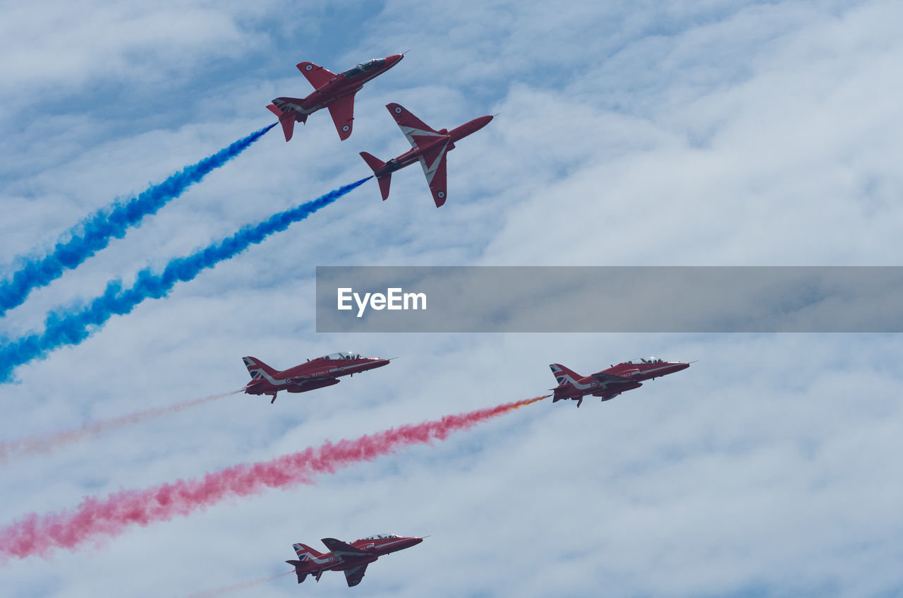 LOW ANGLE VIEW OF AIRSHOW IN FLIGHT AGAINST SKY