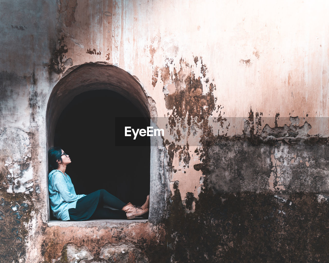 Woman sitting at old window