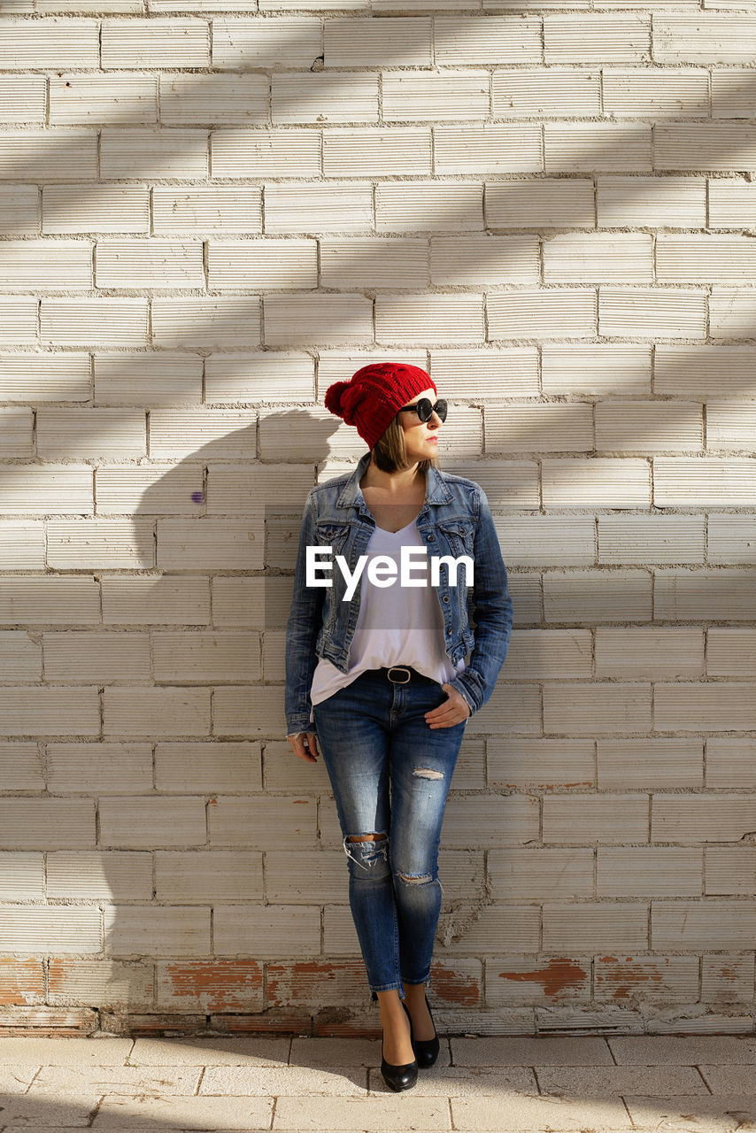 Attractive blond woman posing against wall while looking away