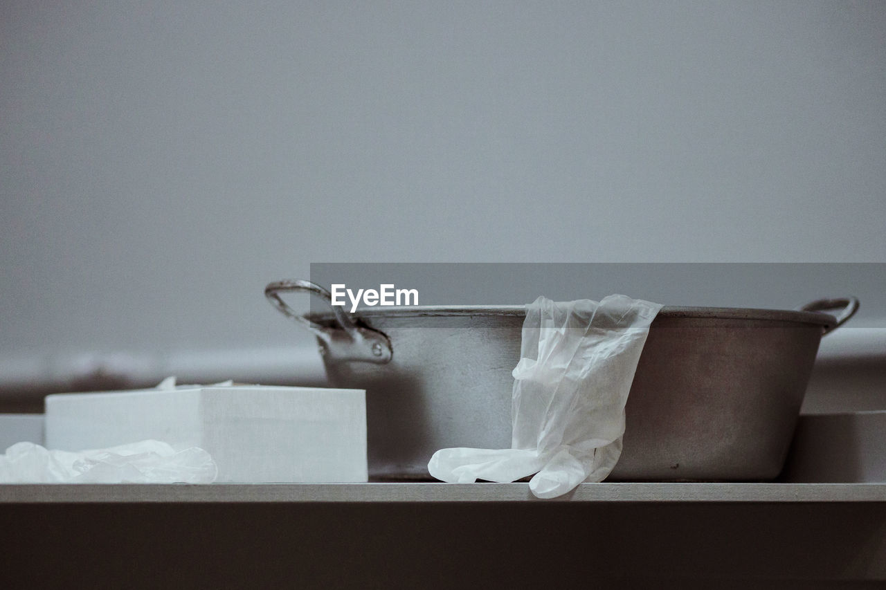 Close-up of glove with container by tissue box on table