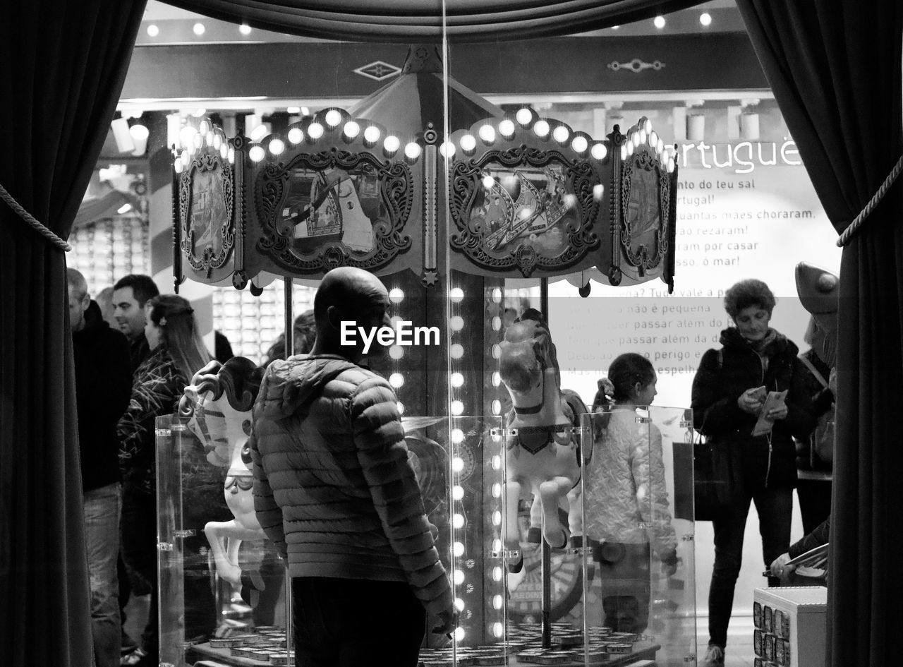 REAR VIEW OF PEOPLE STANDING IN GLASS STORE