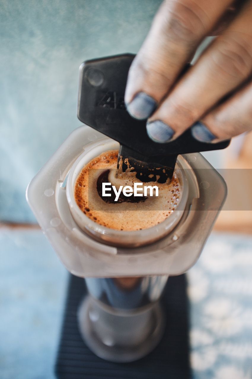 CLOSE-UP OF HAND HOLDING COFFEE CUP