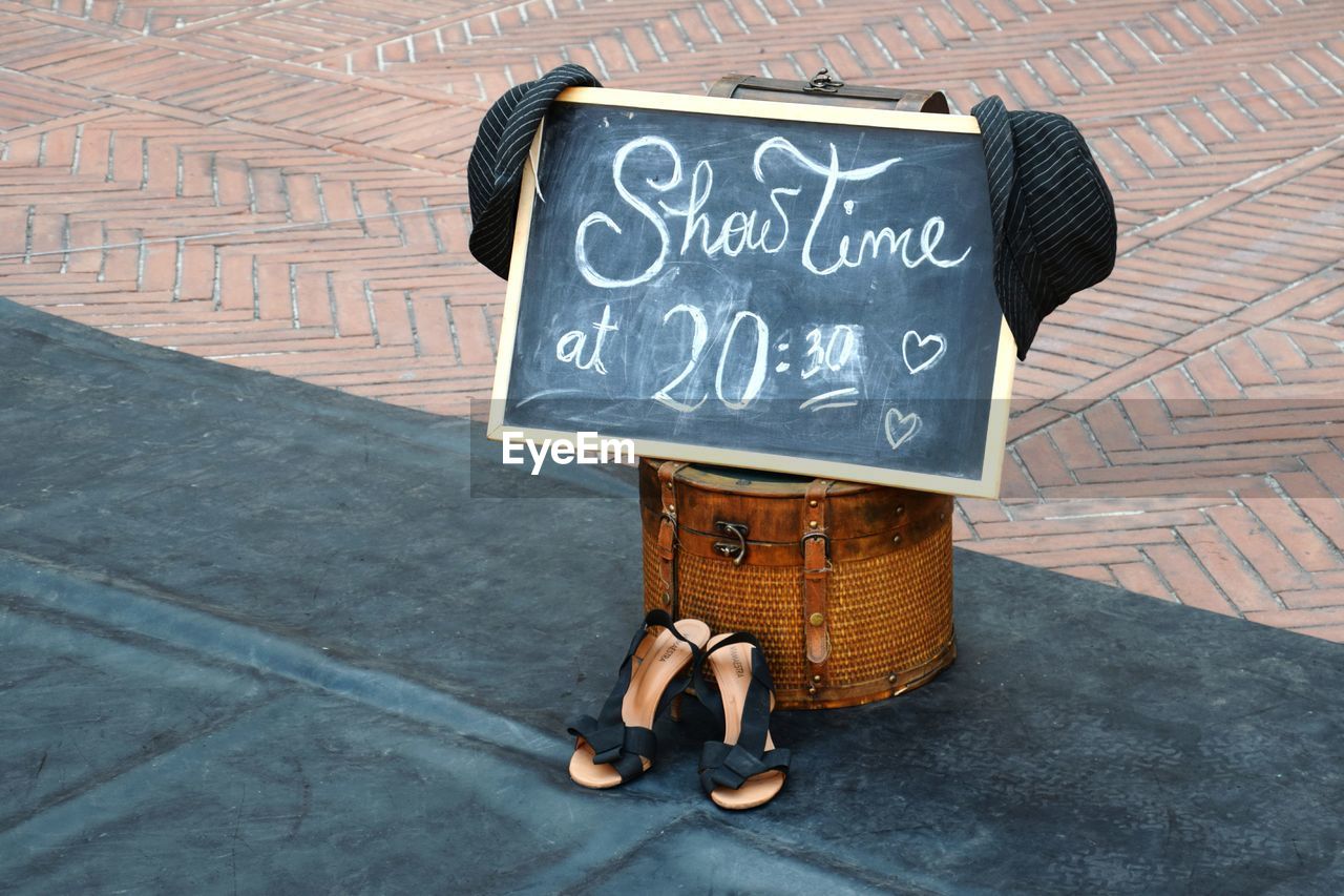 Writing slate with message and sandals on footpath