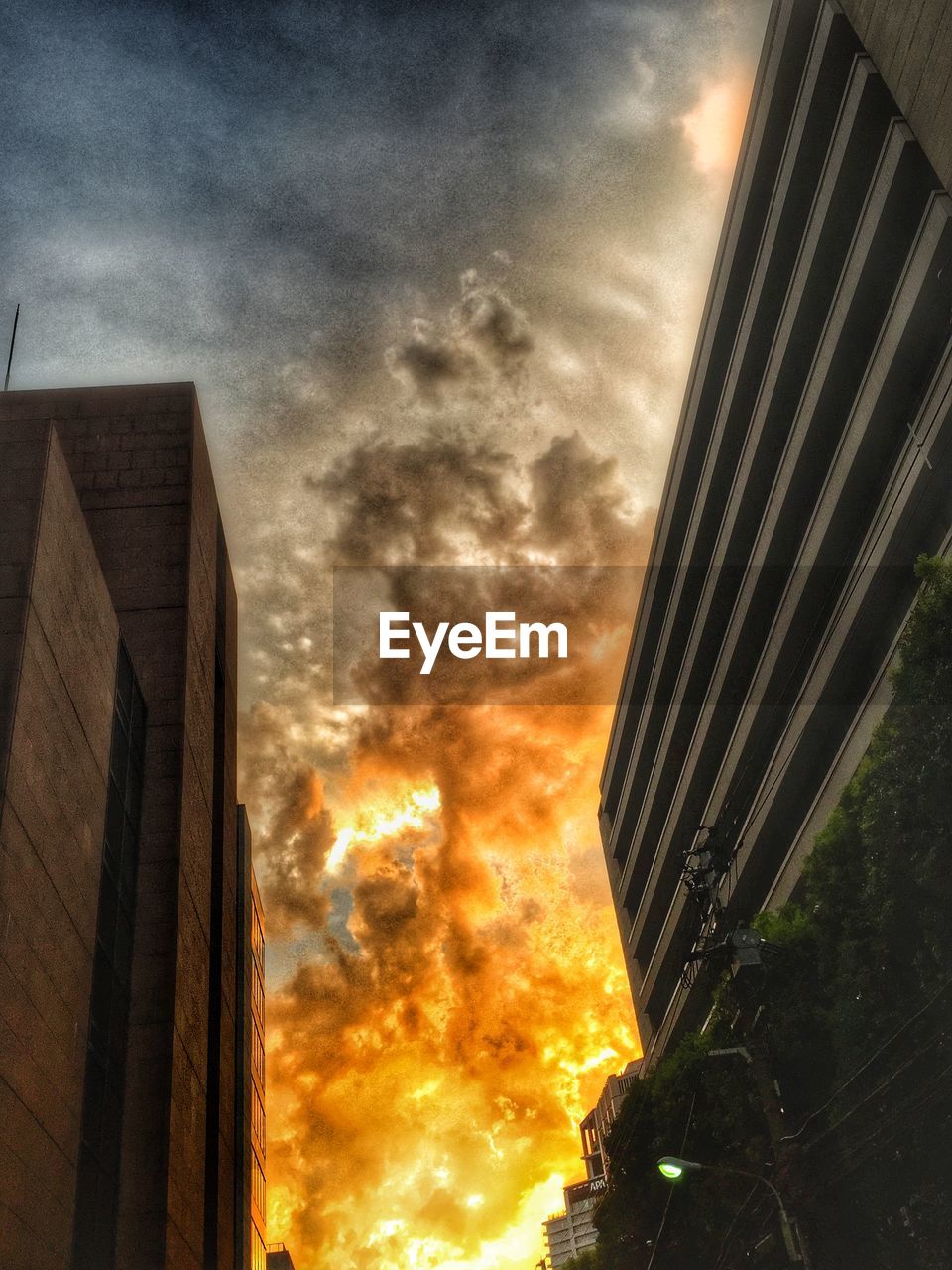 LOW ANGLE VIEW OF BUILDINGS AGAINST CLOUDY SKY AT SUNSET