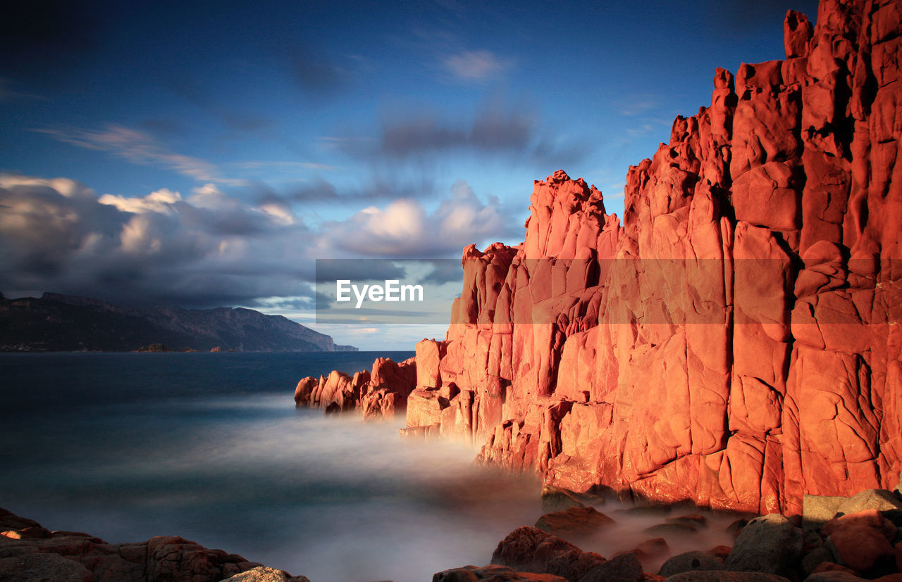 Rock formations by sea against sky during sunset