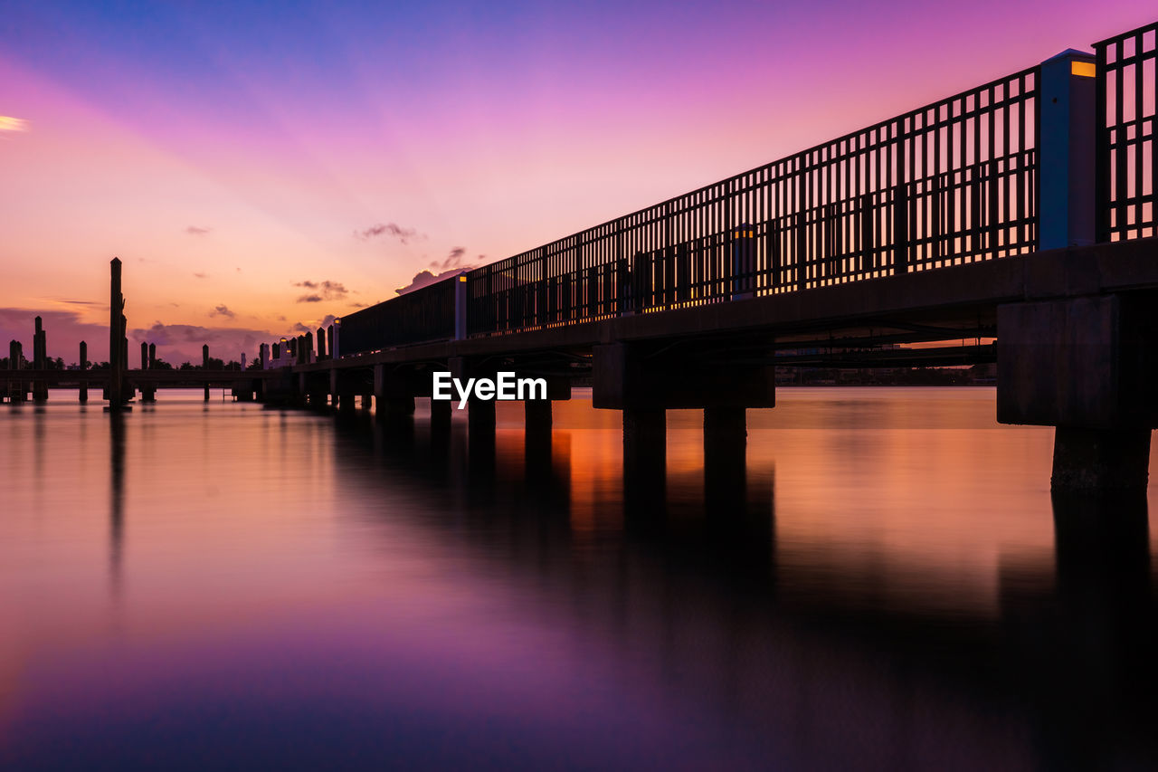 reflection, architecture, water, sky, evening, sunset, dusk, built structure, transportation, bridge, nature, night, cityscape, pier, twilight, city, travel destinations, horizon, no people, cloud, beauty in nature, outdoors, sea, beam bridge, tranquility, silhouette, building exterior, travel, scenics - nature