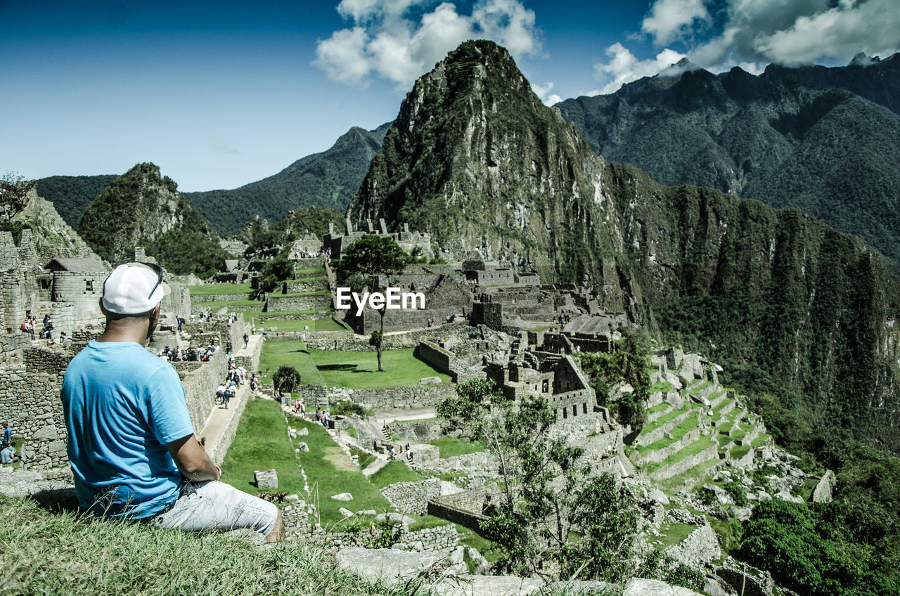 Rear view of man looking at mountains against sky