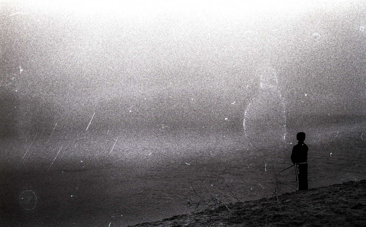 one person, water, darkness, fog, standing, nature, black and white, sky, men, silhouette, sea, leisure activity, beauty in nature, full length, night, astronomical object, light, land, monochrome, scenics - nature, wet, lifestyles, monochrome photography, astronomy, star, outdoors, beach, rear view, wave, mist, horizon, child, snow, tranquility, childhood, rain