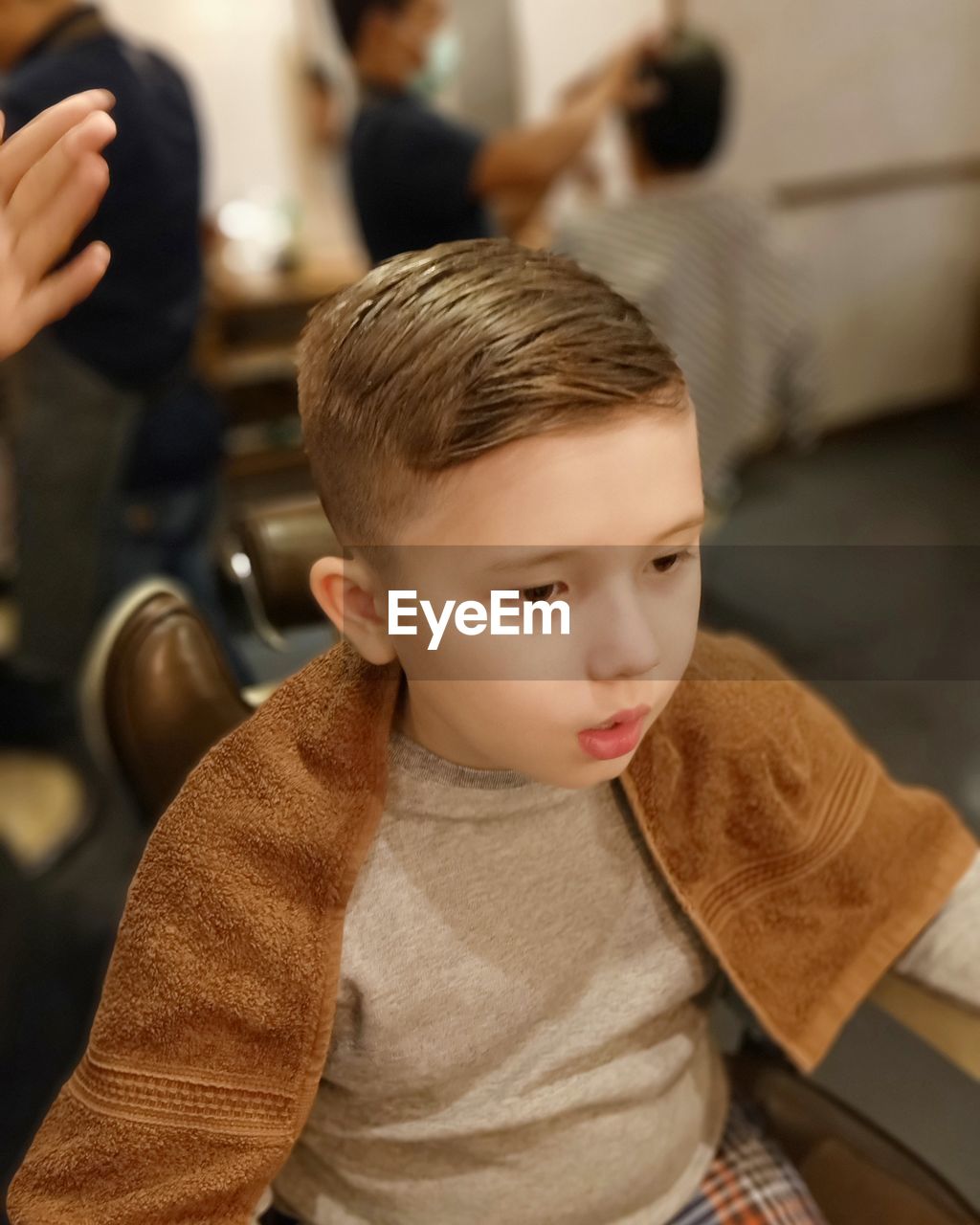 High angle view of boy looking away while sitting in hair salon