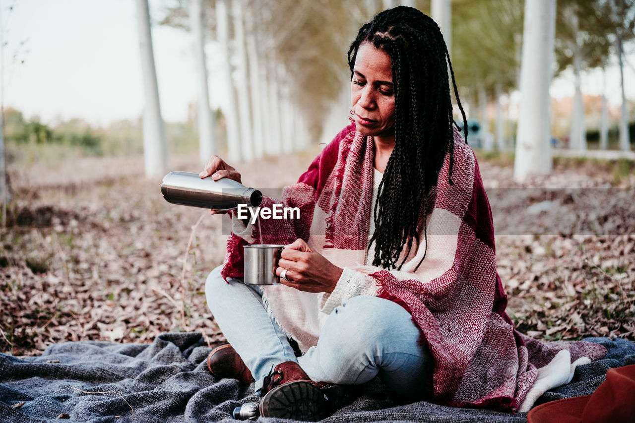 Young woman looking away while sitting on land