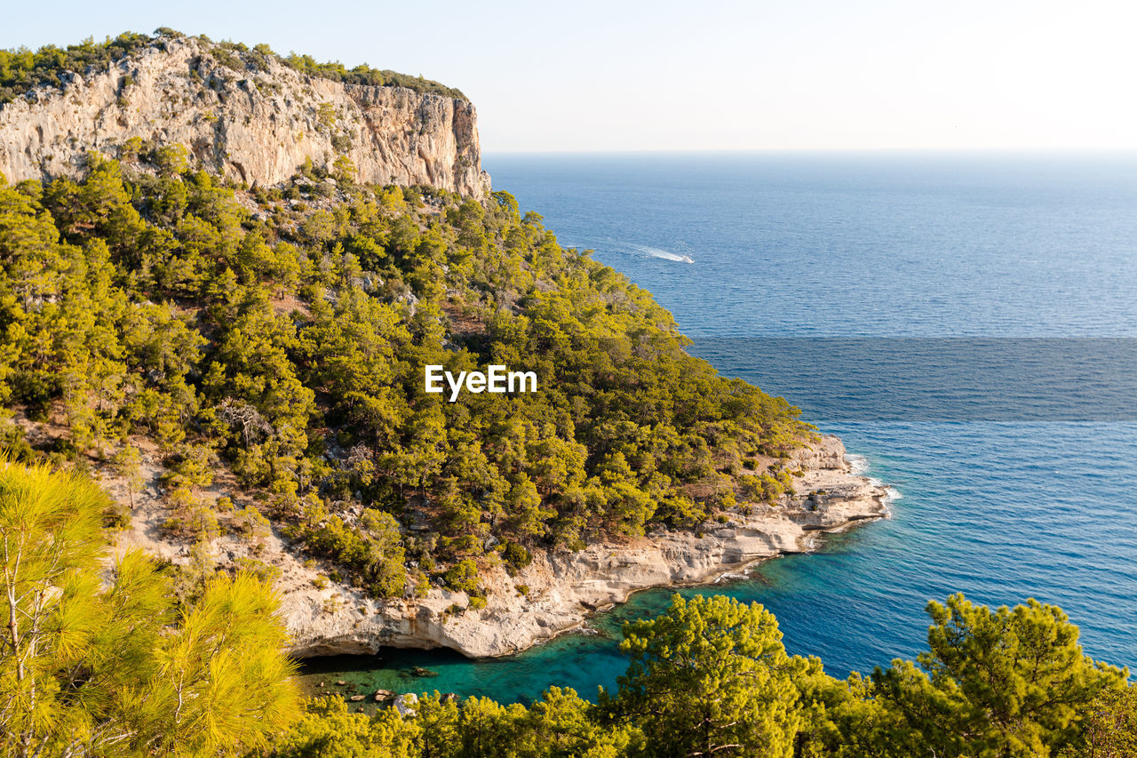 Big rock with forest and azure sea in summer