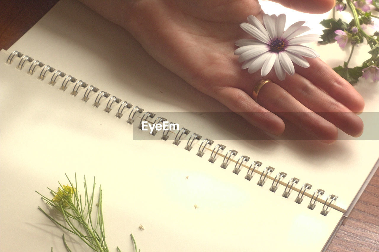 HIGH ANGLE VIEW OF HAND HOLDING TEXT ON WHITE TABLE