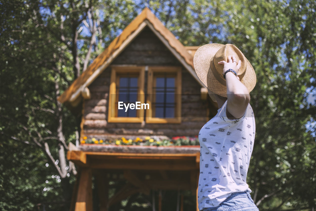 Woman with straw hat looking at wooden cabin