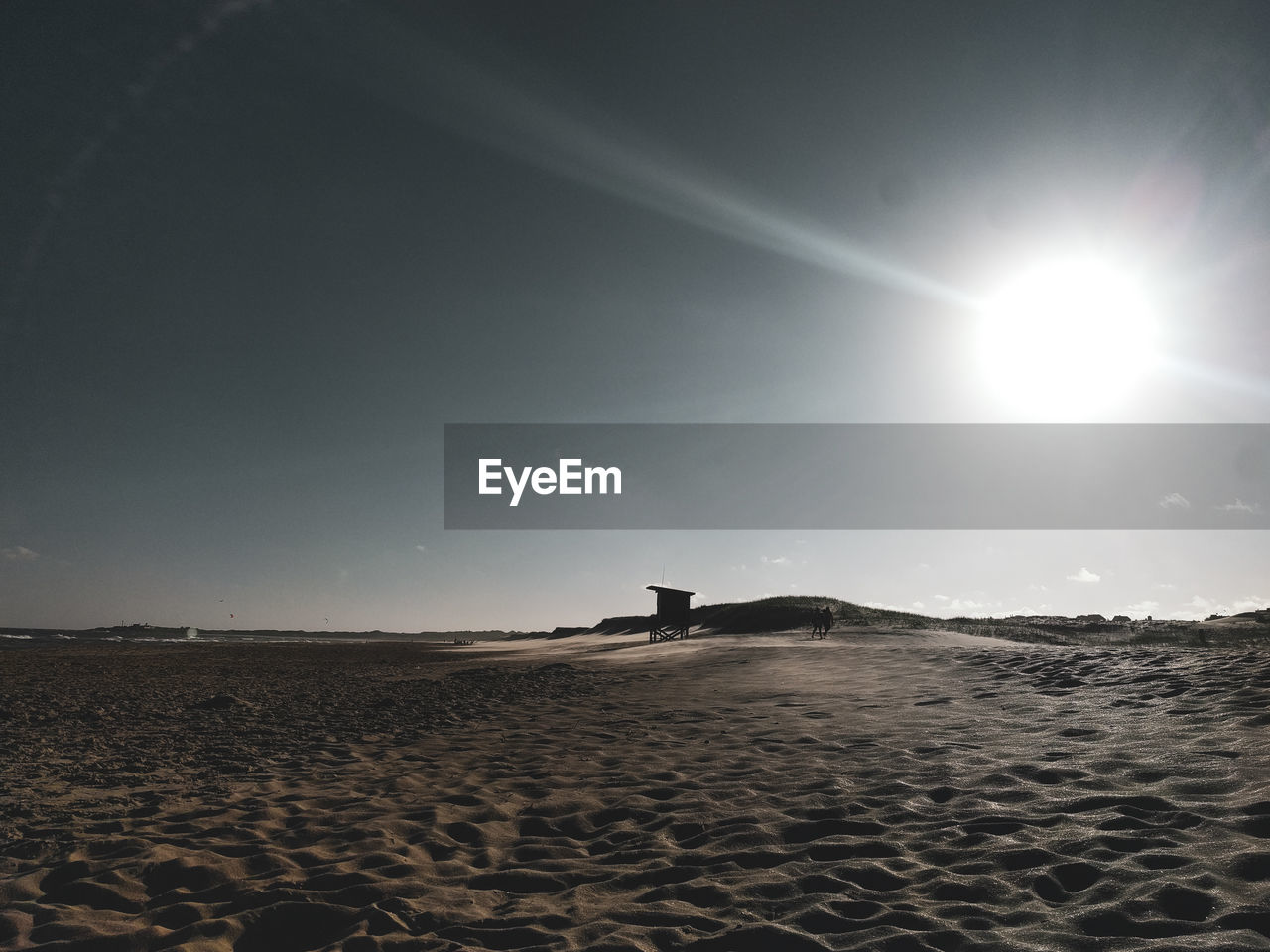 Scenic view of beach against bright sun