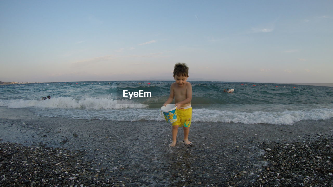 Boy on beach against sky