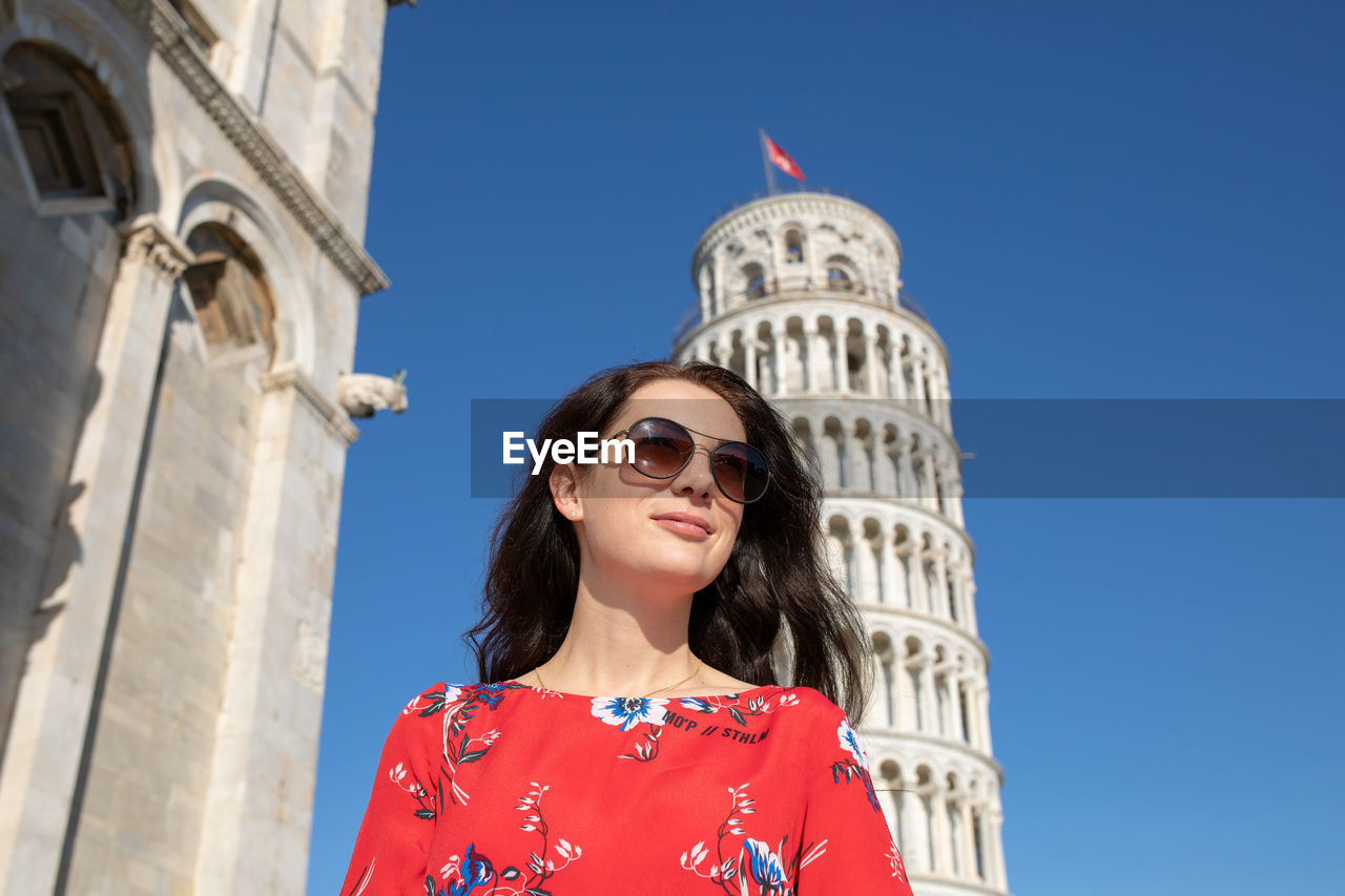 Woman wearing sunglasses while standing against leaning tower of pisa