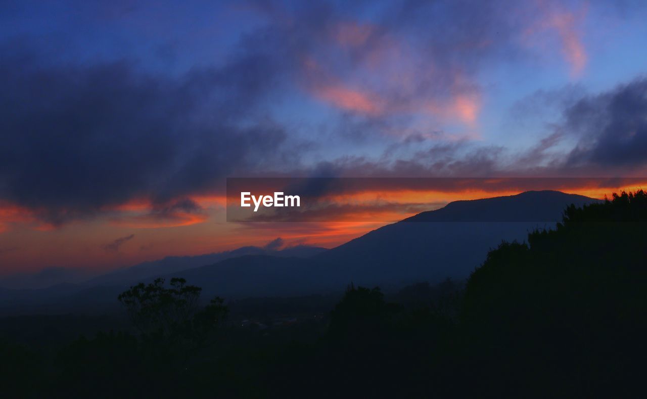 SILHOUETTE OF MOUNTAIN AGAINST SKY DURING SUNSET